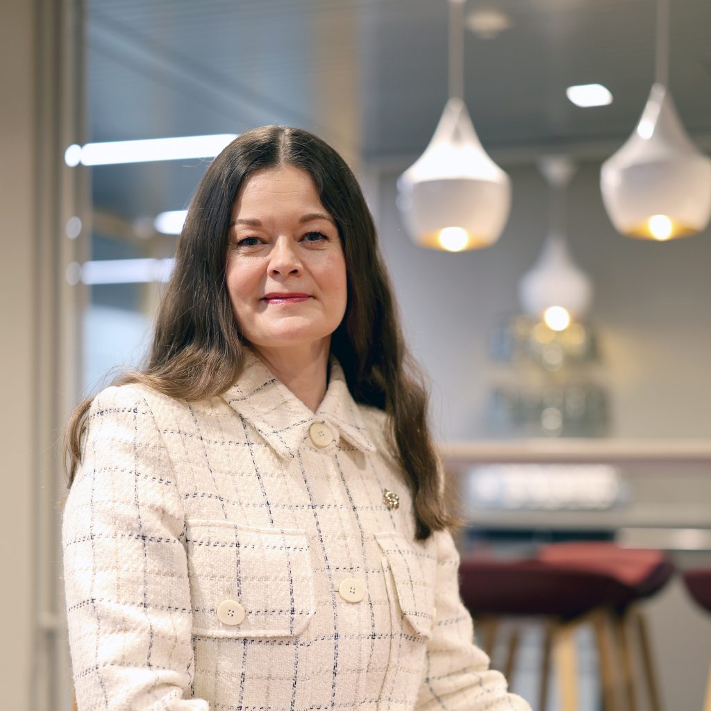 Valtiokonttorin pääjohtaja Liisa Räsänen istuu kahviaulassa ja katsoo kameraan.