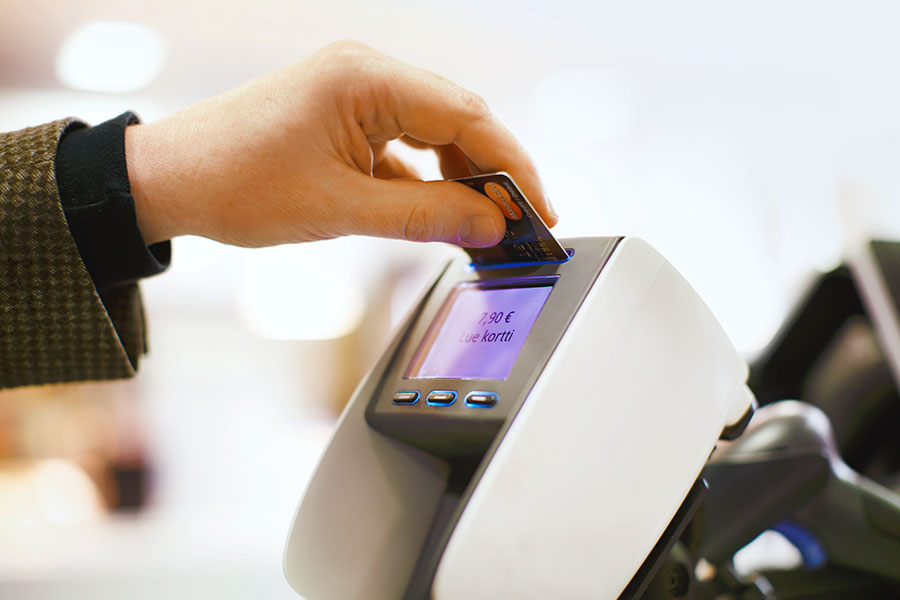 Mies maksaa ostoksia pankkikortilla maksupäätteellä.