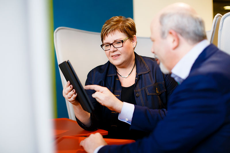 Keski-ikäinen mies ja nainen tutkivat yhdessä tabletilta verkkosisältöjä.