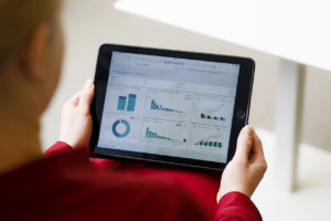 A person holds an iPad that shows statistics.
